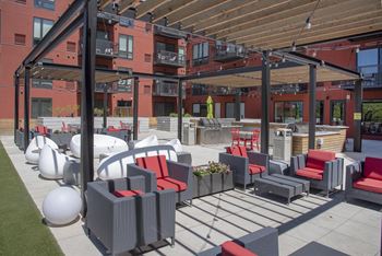 Large outdoor patio with comfortable seating options shaded by pergolas. Grilling stations and entertainment bar area is centrally located in this outdoor space.